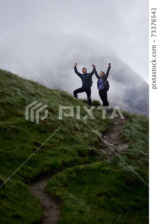 Happy young couple standing on grassy hill. 73376541