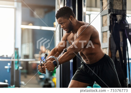 Young black athlete training triceps on block exerciser in gym 73376773
