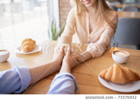 Young couple in love having lunch at cafe, holding hands, drinking coffee, closeup view 73376932