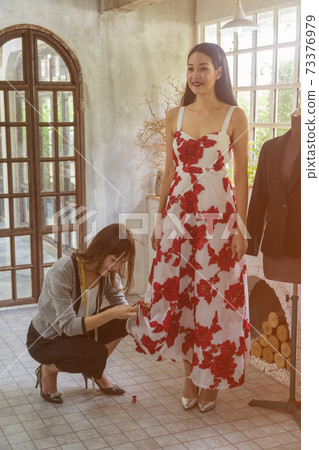 Asian female fashion designers adjusting dress on model in the studio Asian female fashion designers adjusting dress on model in the studio 73376979