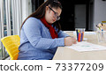 Asian girl with Down's syndrome drawing picture in art class. Concept disabled kid learning. 73377209