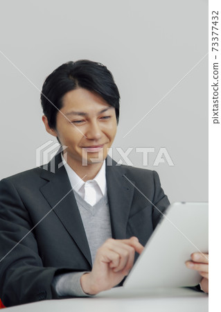 A businessman operating a tablet PC 73377432