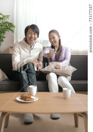 看電視的夫婦使用與智能手機的遙控 73377587
