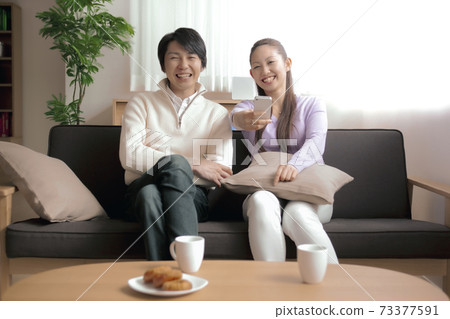 A couple looking at a television using a remote control with a smartphone A couple looking at a television using a remote control with a smartphone 73377591