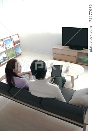 男人和女人坐在沙發上，拿著一台平板電腦 73377676