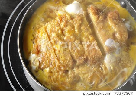 Cooking scene where cutlets and onions are boiled in a parent-child pot compatible with an IH cooking heater and bound with eggs Cooking scene where cutlets and onions are boiled in a parent-child pot compatible with an IH cooking heater and bound with eggs 73377867