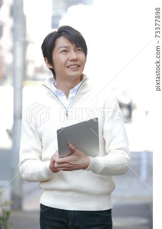 一個人用平板電腦在城市中行走 一個人用平板電腦在城市中行走 73377898