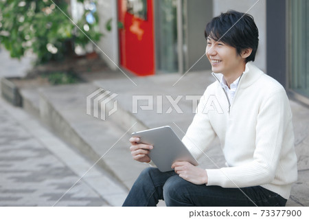 一個男人坐在城市的平板電腦 一個男人坐在城市的平板電腦 73377900