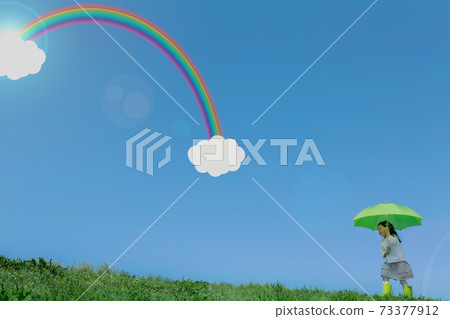A girl walking with a green umbrella A rainbow and a cloud in the blue sky A girl walking with a green umbrella A rainbow and a cloud in the blue sky 73377912