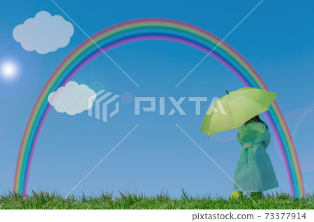 穿雨衣和顯示綠色傘彩虹和雲彩的女孩的後面 穿雨衣和顯示綠色傘彩虹和雲彩的女孩的後面 73377914