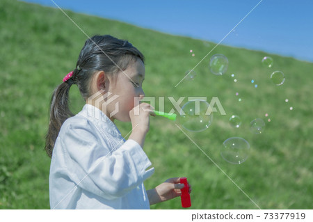 The profile of a girl blowing soap bubble 73377919