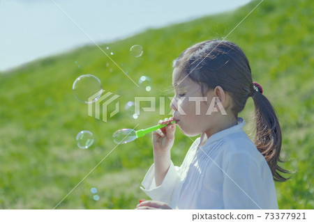 The profile of a girl blowing soap bubble 73377921