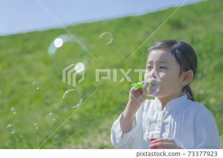Girls blowing soap bubbles 73377923