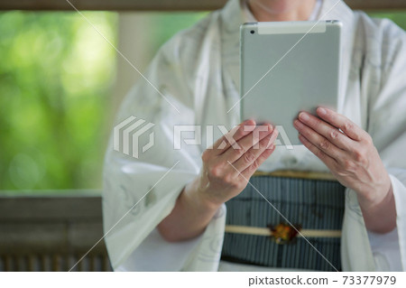 A woman in kimono with a tablet PC A woman in kimono with a tablet PC 73377979