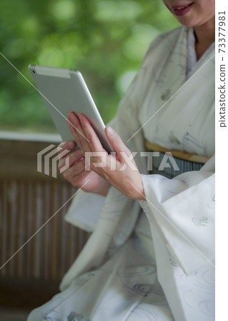 A woman in kimono with a tablet PC A woman in kimono with a tablet PC 73377981