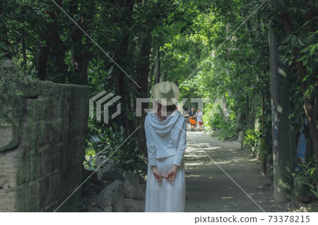 The back of a woman wearing a straw hat The back of a woman wearing a straw hat 73378215