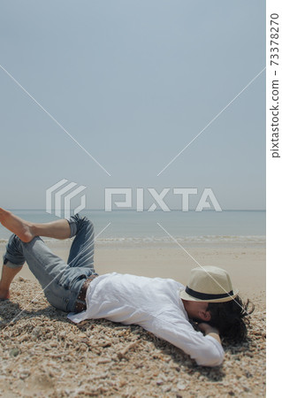 A man lying down on a sandy beach A man lying down on a sandy beach 73378270