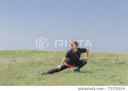 A woman stretching in the meadow A woman stretching in the meadow 73378324