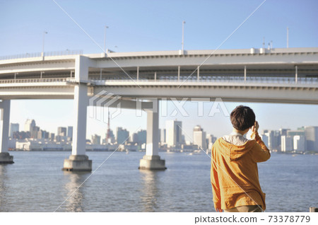 A woman's appearance speaking on a smartphone facing the Rainbow Bridge A woman's appearance speaking on a smartphone facing the Rainbow Bridge 73378779