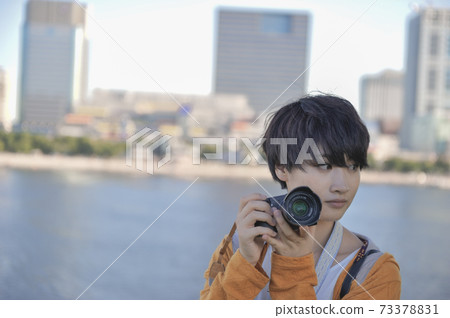 A woman holding a camera and Odaiba Seaside Park at dusk A woman holding a camera and Odaiba Seaside Park at dusk 73378831