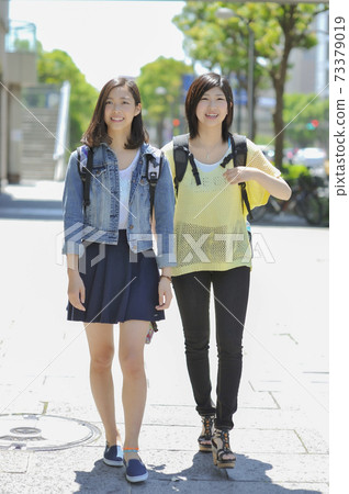 Two women walking in the city Two women walking in the city 73379019