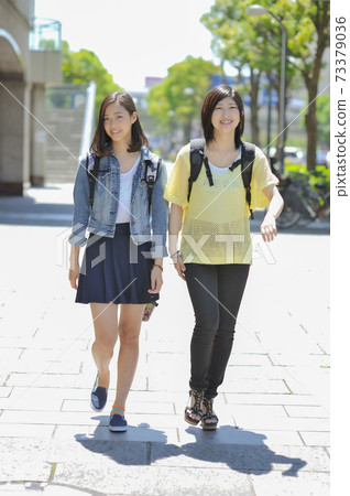 Two women walking in the city 73379036