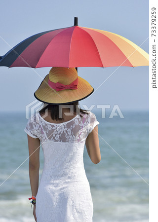 A woman's behind appearing a rainbow colored umbrella at the beach A woman's behind appearing a rainbow colored umbrella at the beach 73379259