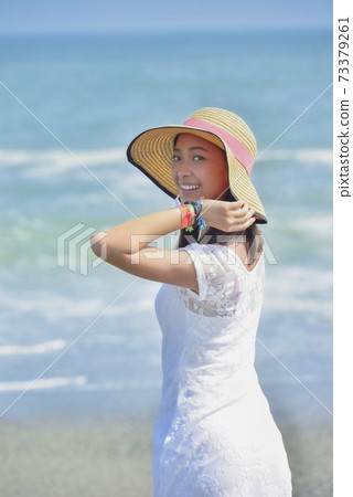 A woman wearing a cap on the beach 73379261
