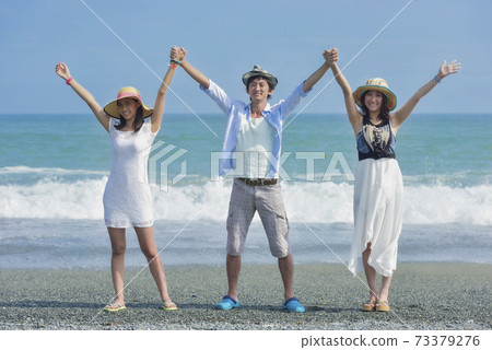 Three young people posing at the beach Three young people posing at the beach 73379276