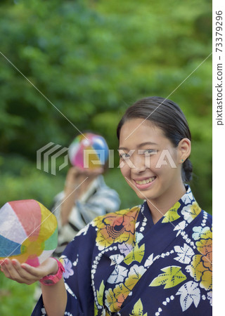 Two women in a yukata playing with a paper breeze Two women in a yukata playing with a paper breeze 73379296