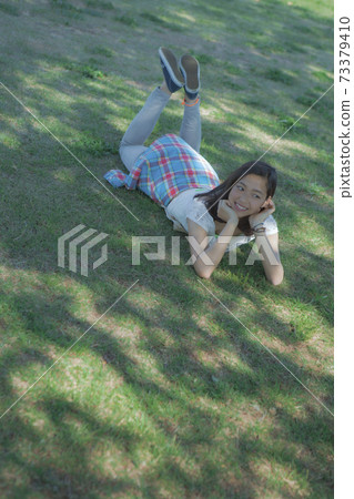 A woman lying down on the lawn A woman lying down on the lawn 73379410