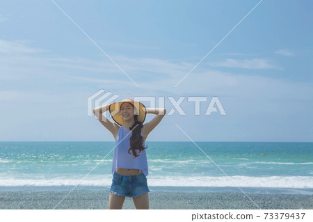戴在海灘的婦女一個草帽 戴在海灘的婦女一個草帽 73379437