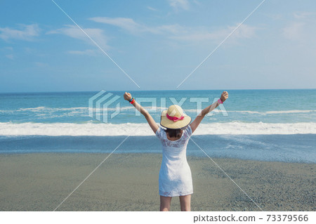 Back of a woman posing at the beach Back of a woman posing at the beach 73379566
