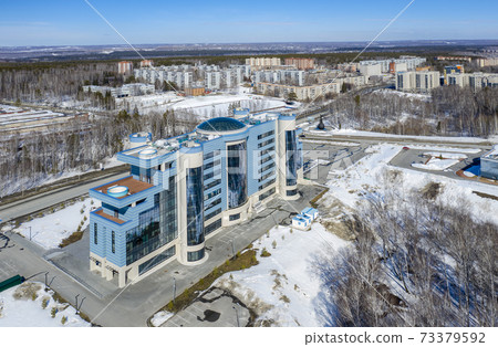 Aerial view of the modern building in the Siberian city of Koltsovo, Russia, in sunny snowy weather Aerial view of the modern building in the Siberian city of Koltsovo, Russia, in sunny snowy weather 73379592