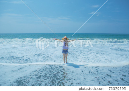 A woman standing at the beach A woman standing at the beach 73379595