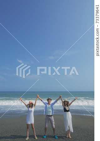 Three young people posing at the beach Three young people posing at the beach 73379641