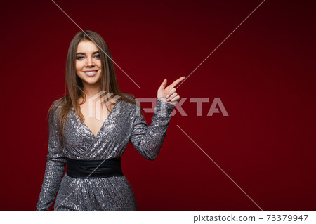 Happy beautiful young lady pointing finger to the Happy beautiful young lady pointing finger to the 73379947