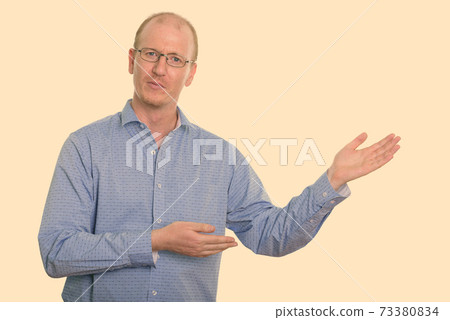 Studio shot of businessman showing something Studio shot of businessman showing something 73380834