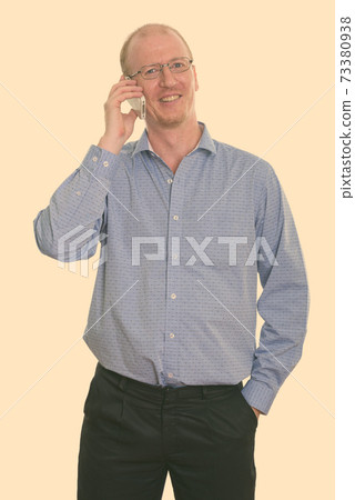 Studio shot of happy businessman smiling while talking on mobile phone Studio shot of happy businessman smiling while talking on mobile phone 73380938
