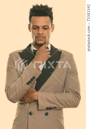 Studio shot of young African businessman thinking while looking down Studio shot of young African businessman thinking while looking down 73381342
