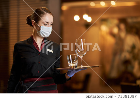 Elegant woman in uniform holding tray with glasses Elegant woman in uniform holding tray with glasses 73381387