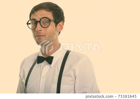 Studio shot of young handsome man wearing eyeglasses with suspenders and bow tie 73381645