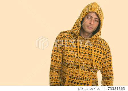 Studio shot of young handsome man thinking and looking down while wearing hoodie 73381863