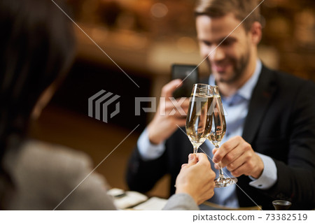 Elegant man taking photo of two champagne glasses 73382519