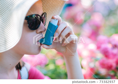 Girl having asthma using asthma inhaler for being healthy 73382937
