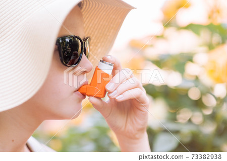 Girl having asthma using asthma inhaler for being healthy 73382938