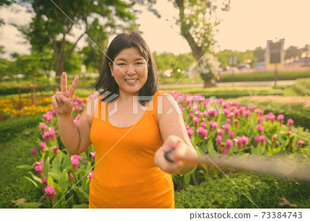 Beautiful overweight Asian woman relaxing at the park in the city of Bangkok, Thailand 73384743