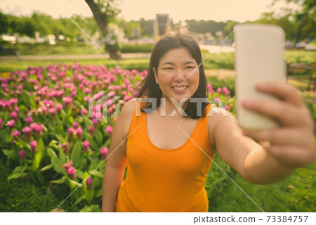 Beautiful overweight Asian woman relaxing at the park in the city of Bangkok, Thailand Beautiful overweight Asian woman relaxing at the park in the city of Bangkok, Thailand 73384757