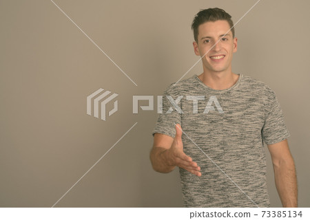 Young handsome man wearing gray shirt against gray background Young handsome man wearing gray shirt against gray background 73385134