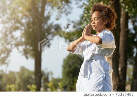 Cute little girl in kimono meditating on the street 73385495
